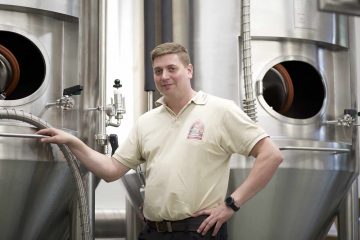 man standing next to beer kegs